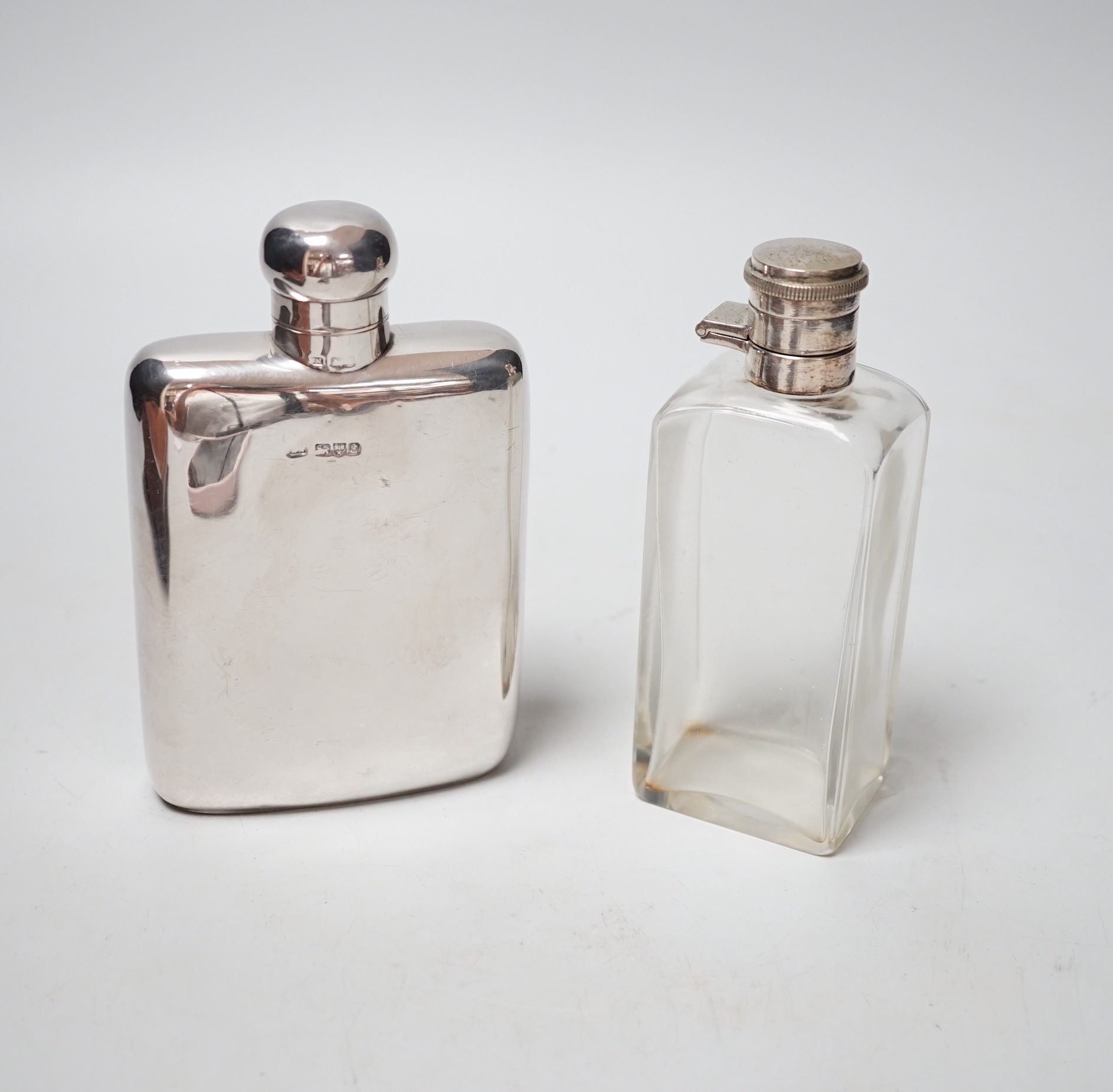 An Edwardian silver hip flask, Chester, 1905, 13.7cm, together with a white metal mounted glass scent flask, housed in an associated? leather carrying case.